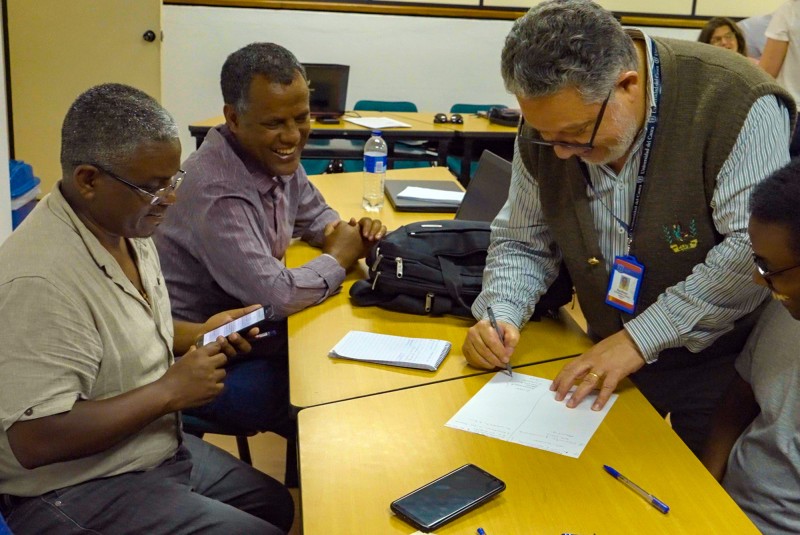 Members of the Ethiopia and Colombia teams smiling as they work together across a table